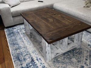 Farmhouse-style coffee table that I built. Brown stain on top, faded white paint on the legs.