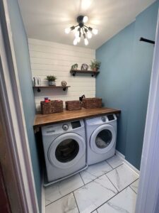 New laundry room featuring a new washer & dryer, tile, shiplap wall, new light fixture, and DIY countertop from wood.