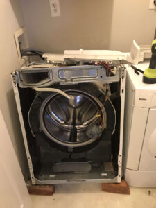 Washer machine with the front face of it off in order to try and fix it.